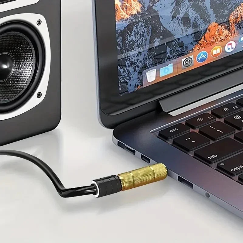 Gold audio adapter connecting a cable to a laptop